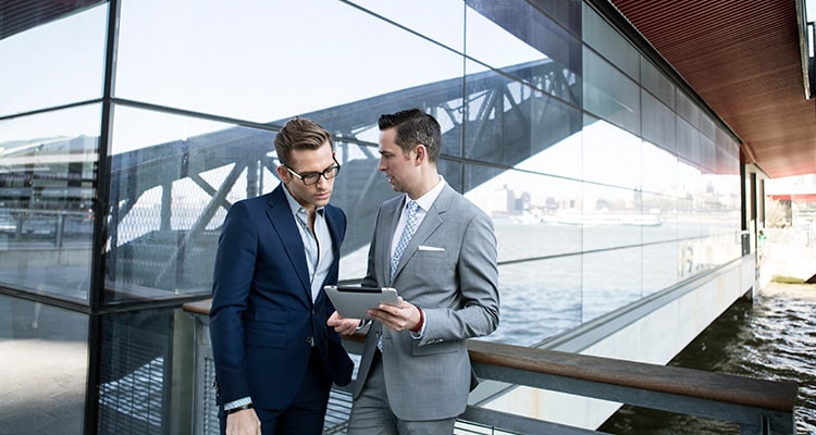 Image of two men talking while looking at an ipad