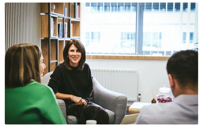 Three people sat around in the office having a chat